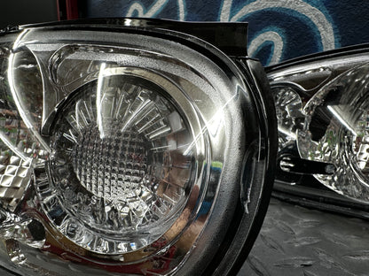 Close-up of the NA Miata clear tail light lens showing the disclosed interior damage on the driver-side unit