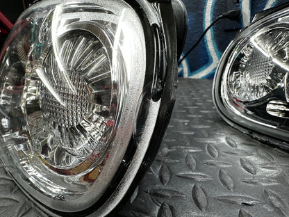 Angled close-up of the clear lens and housing edge on the as-is NA Miata tail light set