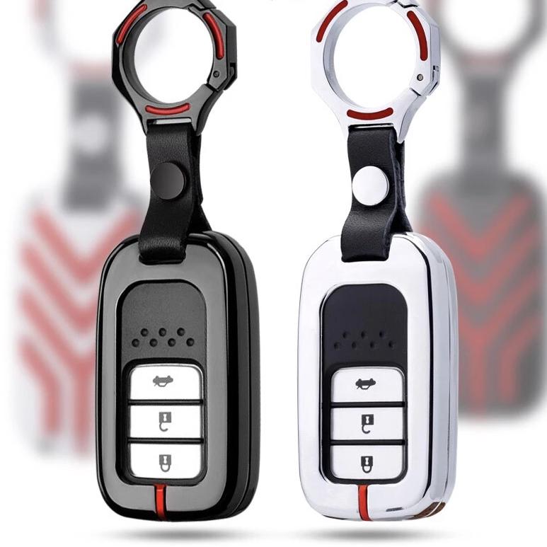Two car key fobs with black and white designs on a blurred background.